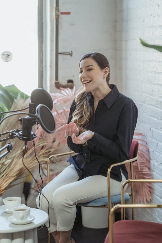 Happy stylish female with long wavy hair smiling and recording with microphone in modern studio